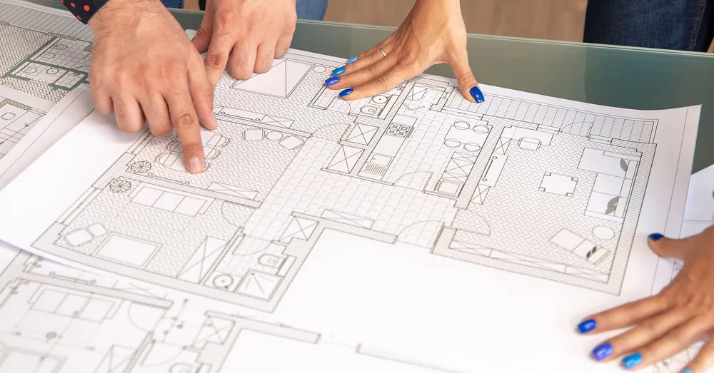 A set of hands pointing to a well drawn detailed plan of a house with textures.